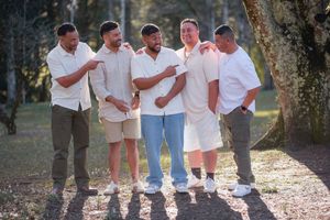 Casual outdoor group photo of people wearing white shirts and jeans against natural backdrop. Hanmer Springs