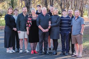 Group photo of family members arranged in casual poses outdoors during fall season.