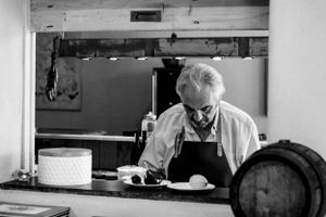 An artisan in white apron works diligently in a workshop with barrels and equipment.