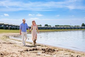 A couple walks along a scenic waterfront path on a sunny summer day.