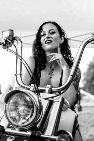 Close-up shots of woman with curly hair posing near motorcycle headlight.