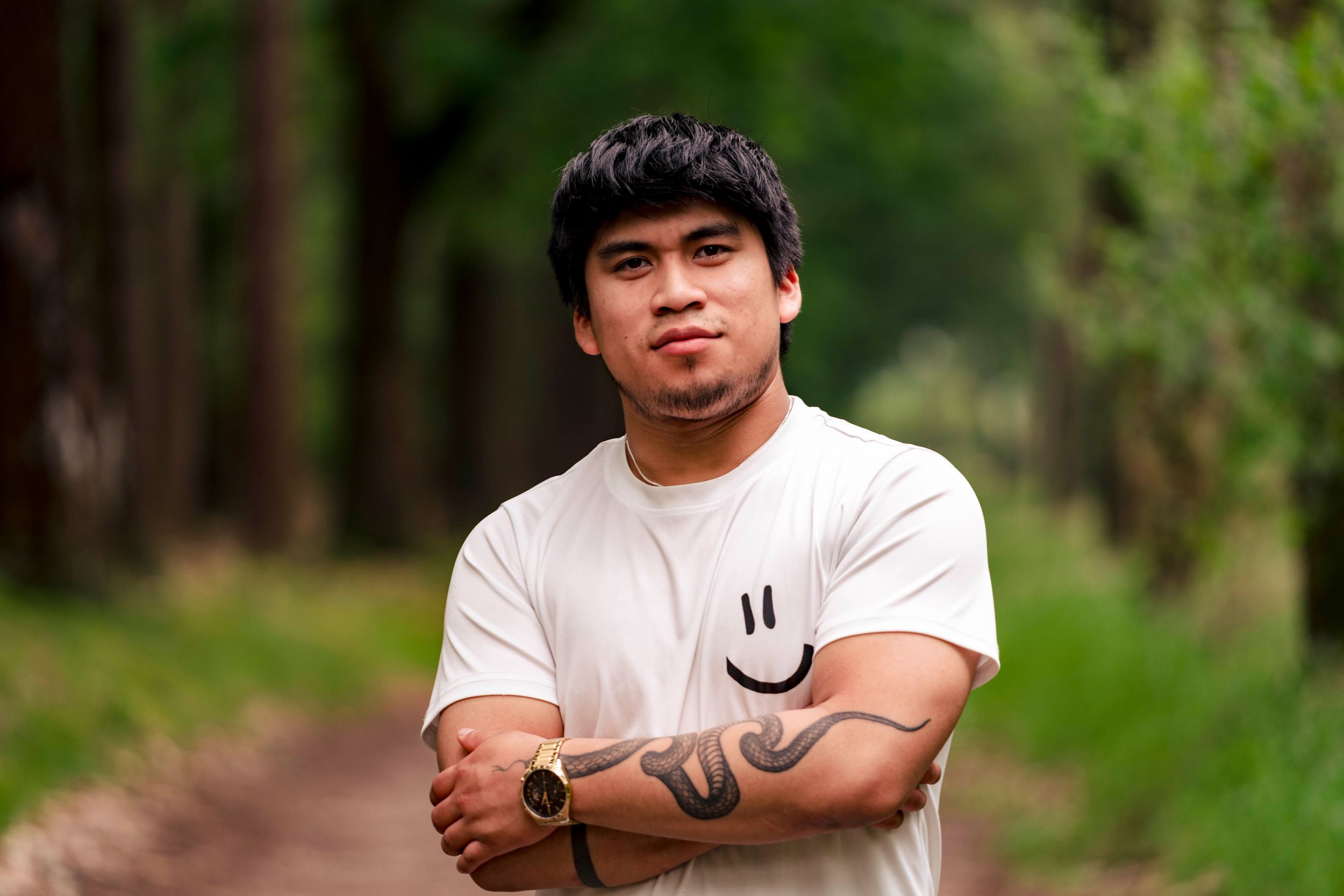 Person in white t-shirt showing muscular arms in outdoor setting.