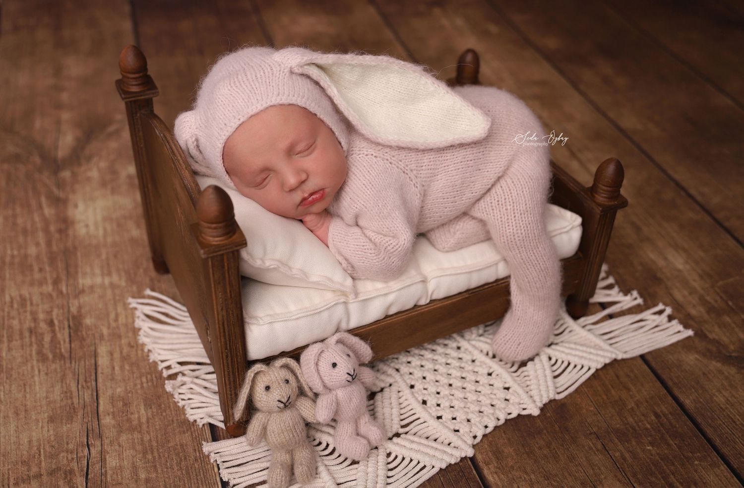 Newborn photography setup with white lace doily on rustic wooden floor.