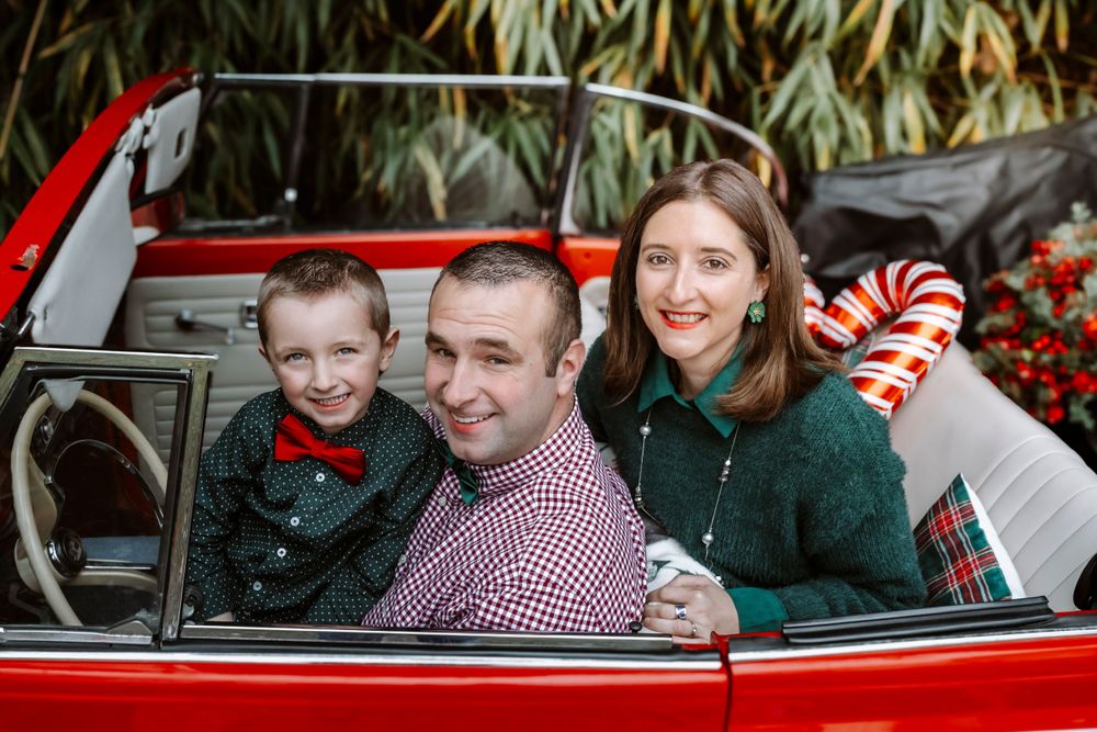 Mini-session photo de Noël 2024 avec une coccinelle VW rouge décorée pour les fêtes, créant une ambiance festive et chaleureuse.