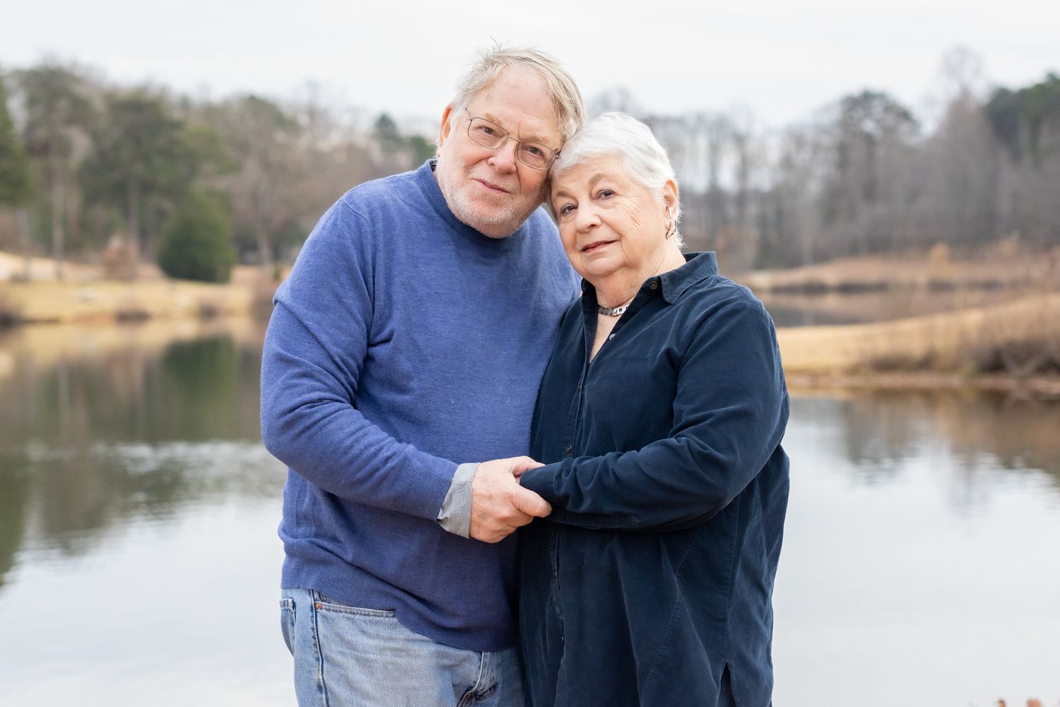 Smiling older couple holding hands and hugging during a golden hour photo session in Windsor, Ontario captured by Tasha Cannaday.