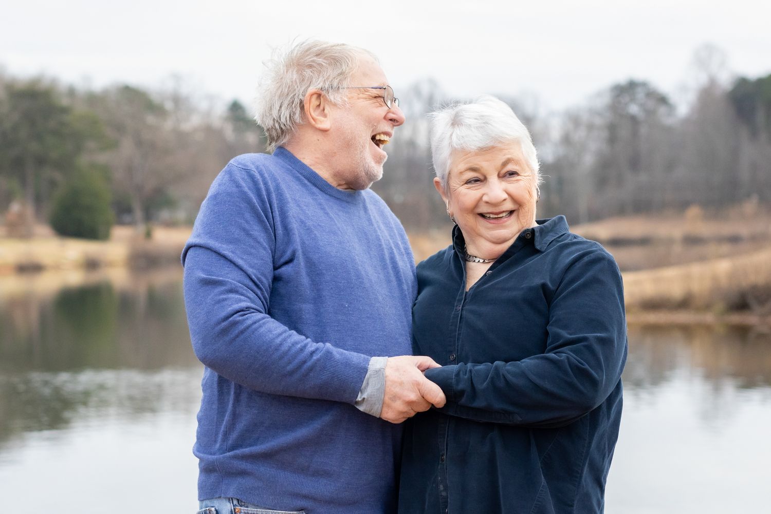 Laughing older couple holding hands and hugging during a golden hour photo session in Windsor, Ontario captured by Tasha Cannaday.