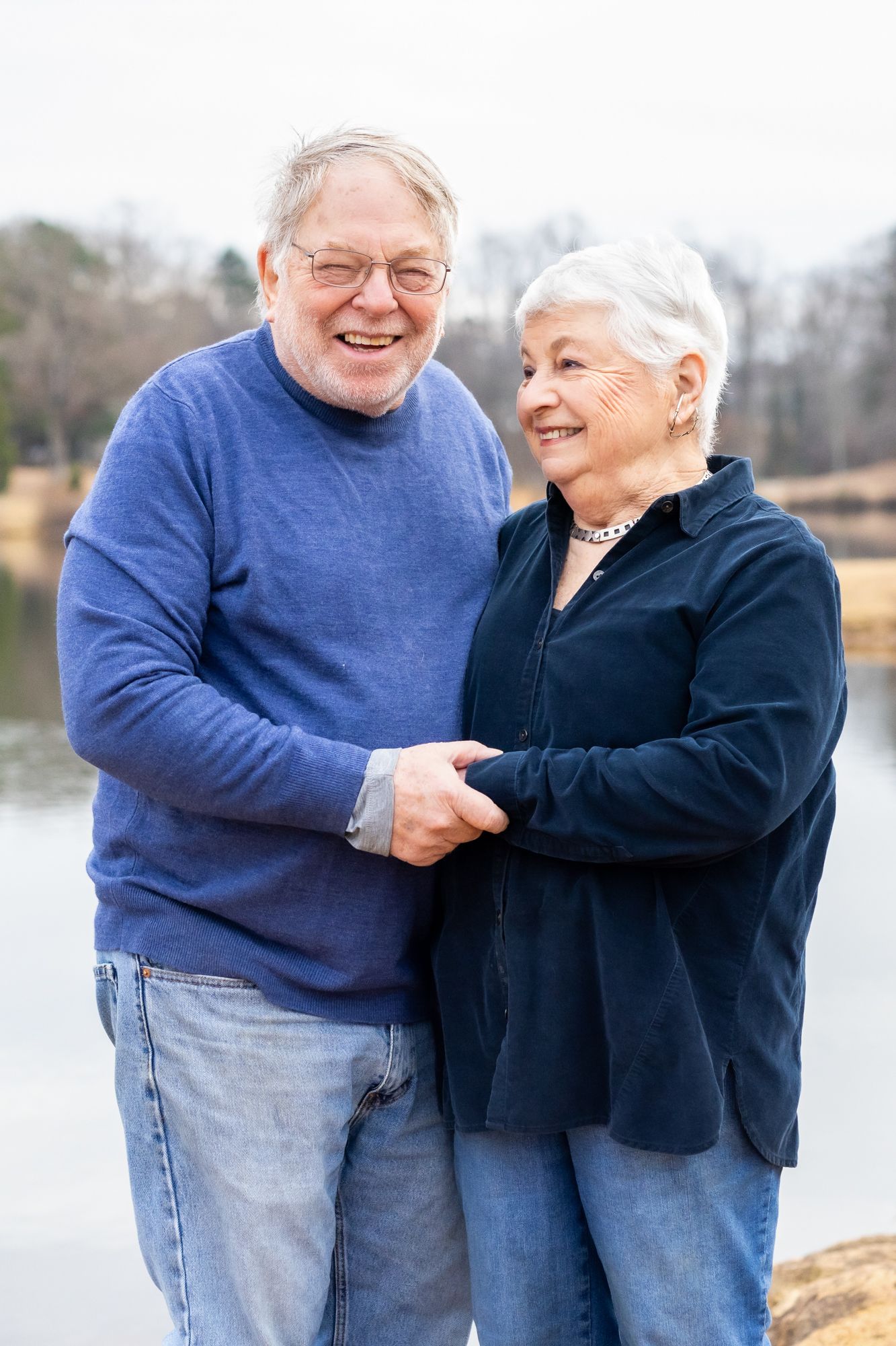 Laughing older couple holding hands and hugging during a golden hour photo session in Windsor, Ontario captured by Tasha Cannaday.