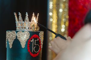 A sparkly silver crown with jewels sits against a blurred background of red and gold bokeh lights.