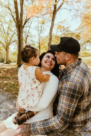 Family of three enjoying a tender moment together during an outdoor fall photoshoot.