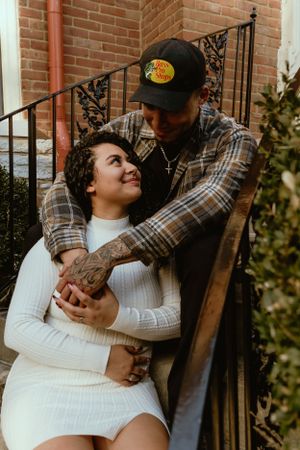 Couple embraces on brick steps during romantic engagement photoshoot.