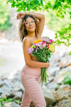 Person holding colorful flower bouquet while posing in nature setting.