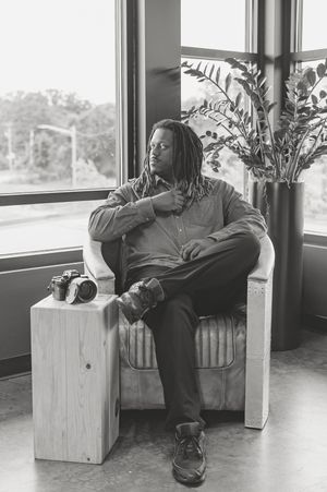 Black and white photo series showing someone seated on a wooden box by a window in four different relaxed poses.