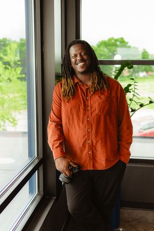 Person in orange button-down shirt smiling by window in sequence of four candid photos.