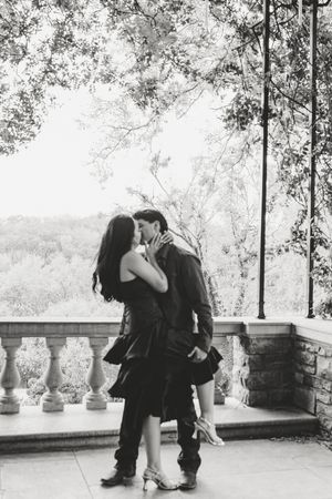 A romantic black and white photo series showing a couple embracing on a terrace with stone balusters in the background.