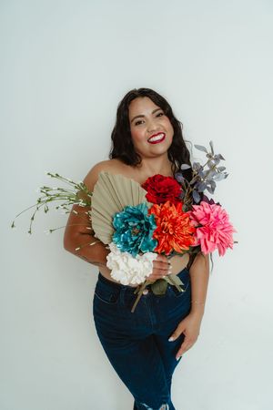 Colorful floral bouquet featuring bright turquoise, red, and pink blooms held against a light background.