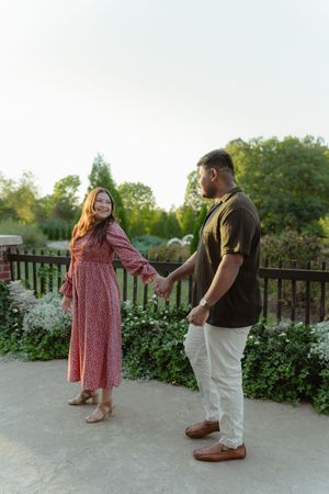 A couple in casual attire shares a tender moment on an outdoor deck surrounded by greenery at sunset.