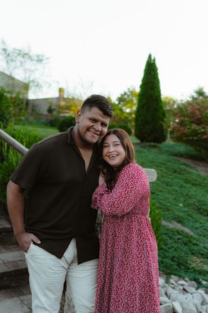 A couple poses together outdoors on a spring evening wearing contrasting black and red floral outfits.