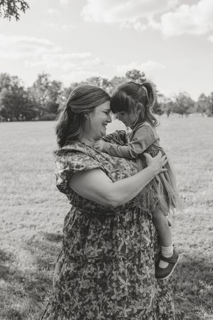 Black and white photos show tender moments between parent and child playing together in a grassy field.