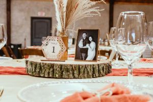 Wedding table centerpiece with wood slice, pampas grass and vintage photographs.