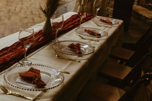 Elegant wedding reception table setting with red accents and crystal glassware.