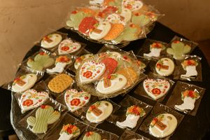 Festive holiday sugar cookies decorated as snowmen with red scarves and carrot noses displayed on a dark surface.