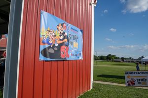 Stuff the Bus 5K race event banner on red barn wall with registration sign and green field in background.