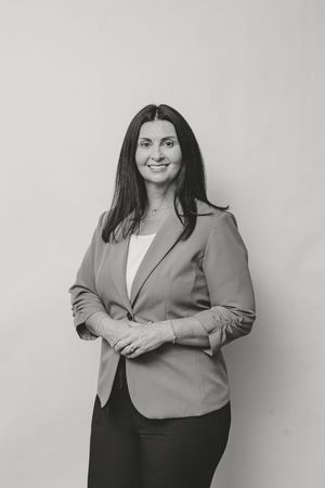 Professional woman in blazer smiling confidently, black and white portrait photo.