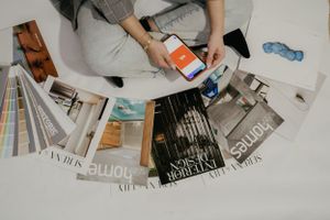 Smartphone and scattered magazines laid out on white surface.