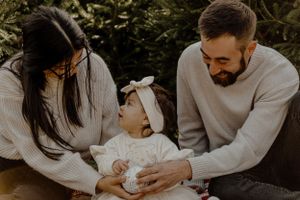 Family sitting together on patterned blanket during outdoor photoshoot.