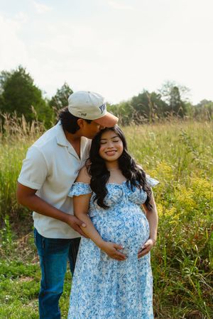 A couple shares tender moments in a wildflower meadow, with the person wearing a blue and white floral dress.