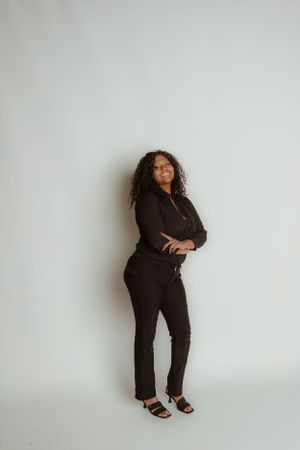 Fashion portrait against white wall in all-black outfit and heels.