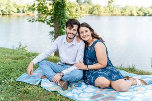 Couple having a romantic picnic by a lake on a sunny afternoon.