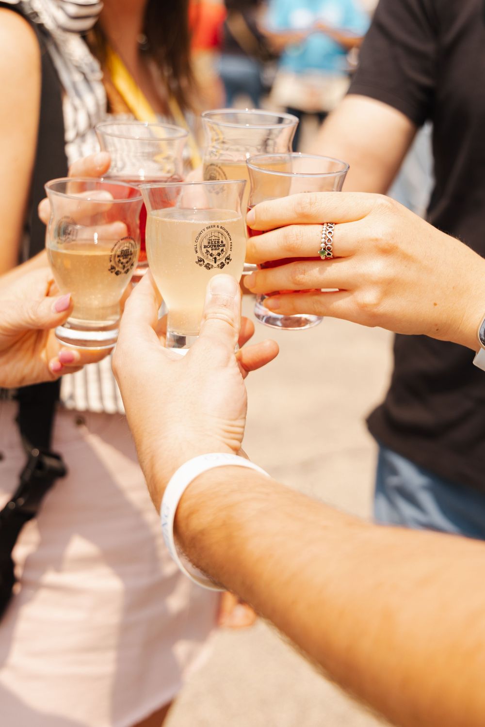 Hands clinking glasses in a celebratory toast outdoors.