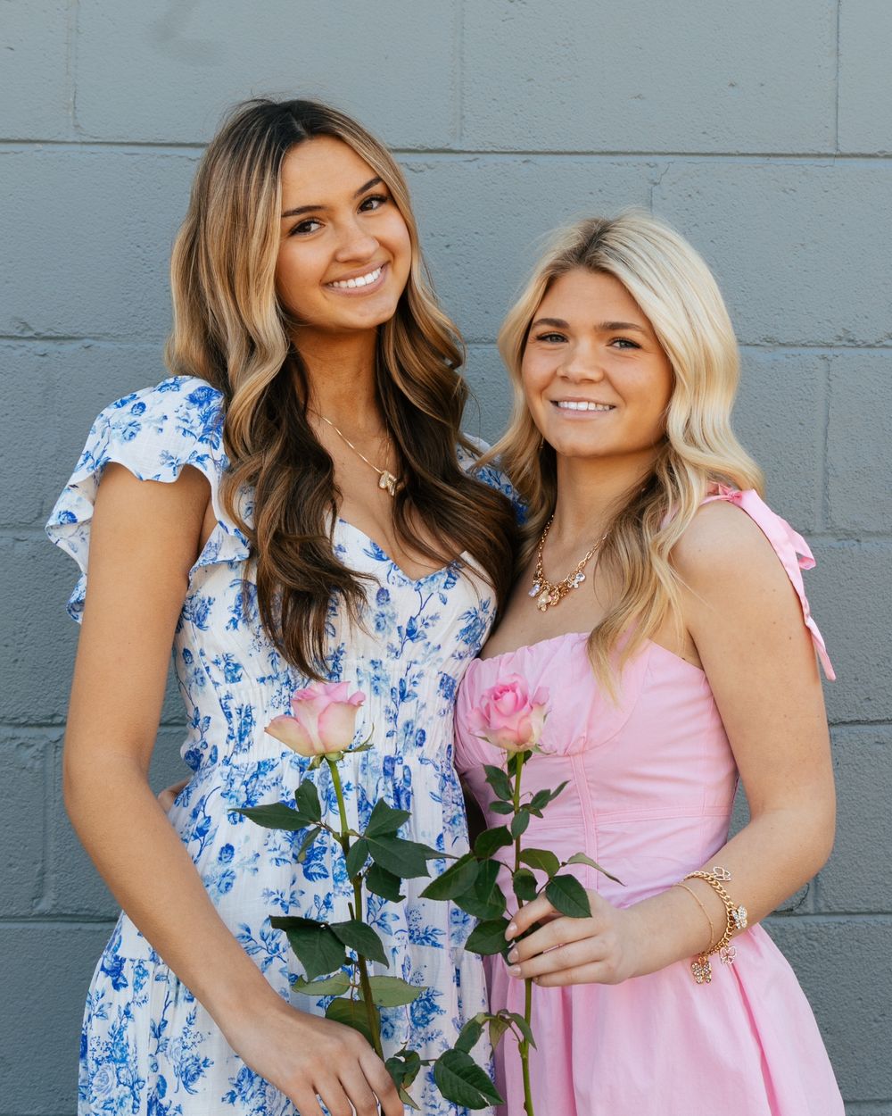 Spring dresses featuring a blue floral print and solid pink design with roses as accessories.