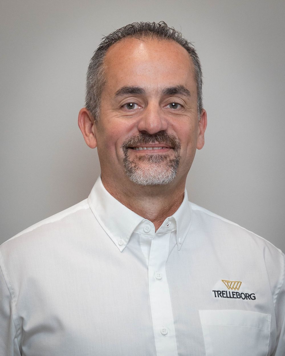 Corporate headshot of a confident man with salt-and-pepper hair in white Trelleborg dress shirt.