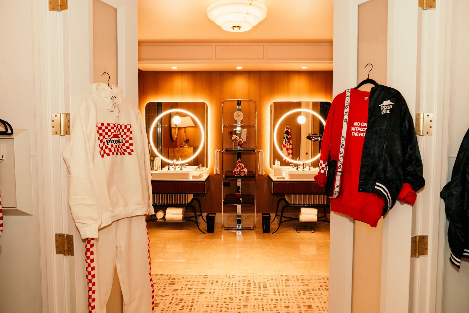 Modern locker room interior with illuminated mirrors and red and white uniforms hanging.