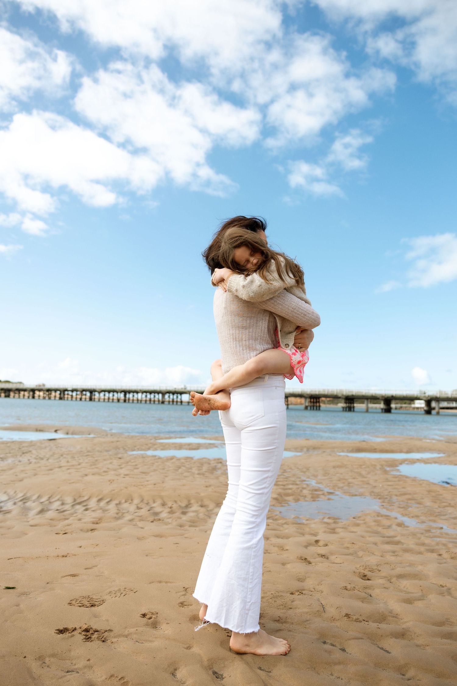 A mother and her children laughing and having fun at the beach.