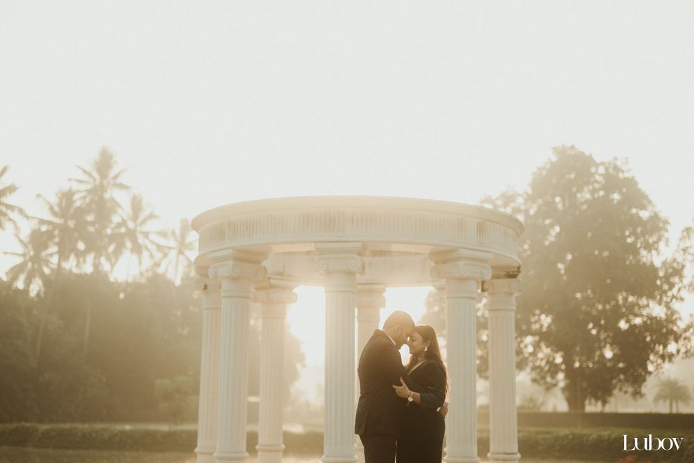 A romantic golden hour photoshoot under a classical columned structure with palm trees in the background.