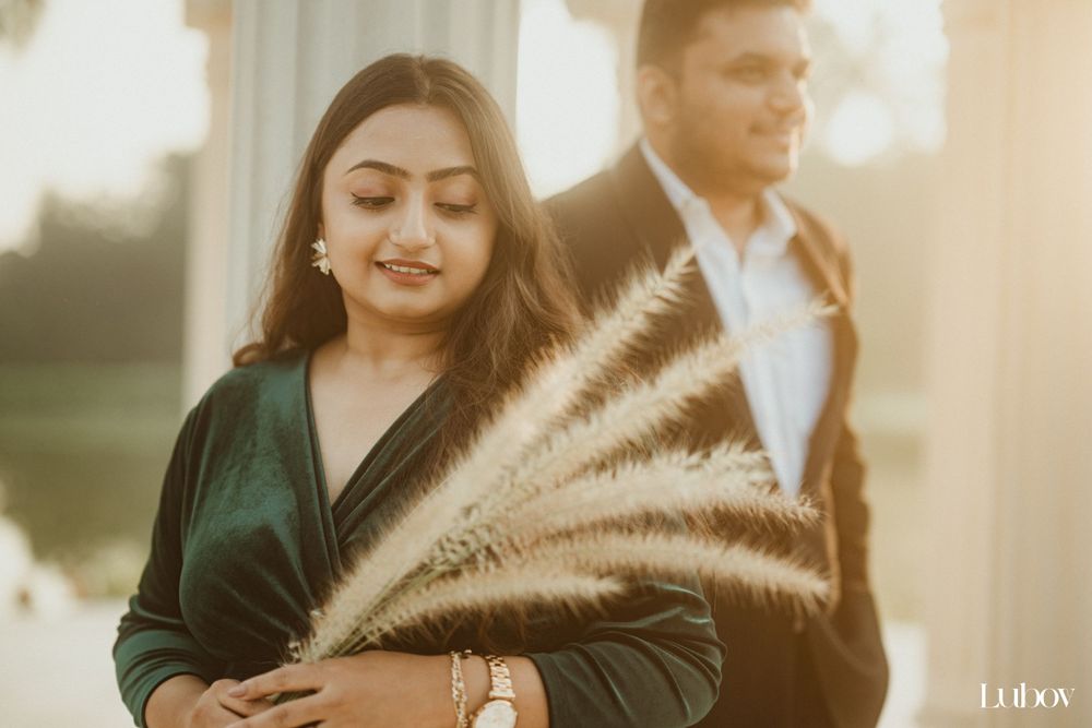 Couple poses at sunset with pampas grass while wearing formal attire.