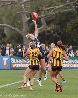 Athletes compete for possession during an intense Australian rules football match on an outdoor field.