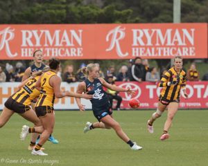 Australian football players compete during a match with Ryman Healthcare advertising banners visible in the background.