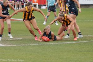 Players compete for possession of a football during an intense match on a grass field.