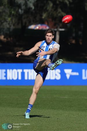 AFL football player reaches out to catch ball during match wearing blue and white striped uniform at sports ground.