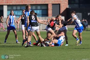 Players from opposing teams battle for possession during an intense Australian Rules Football match on a sunny day.
