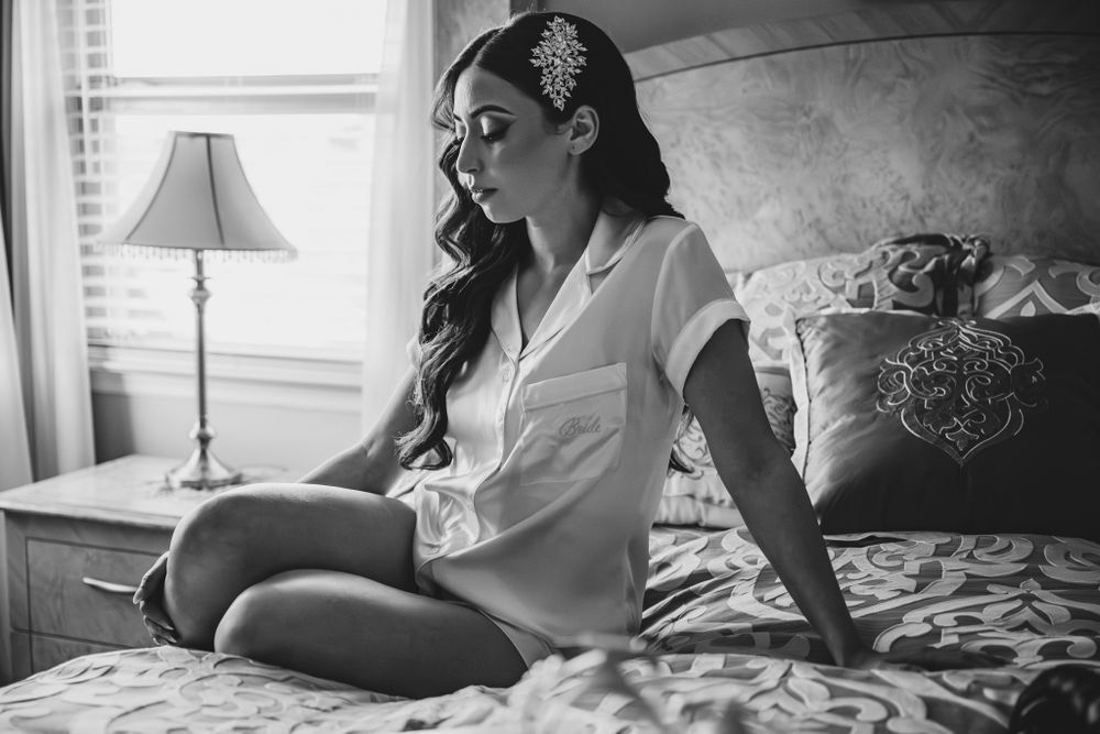 Black and white boudoir photos showing artistic poses on a bed near a window.