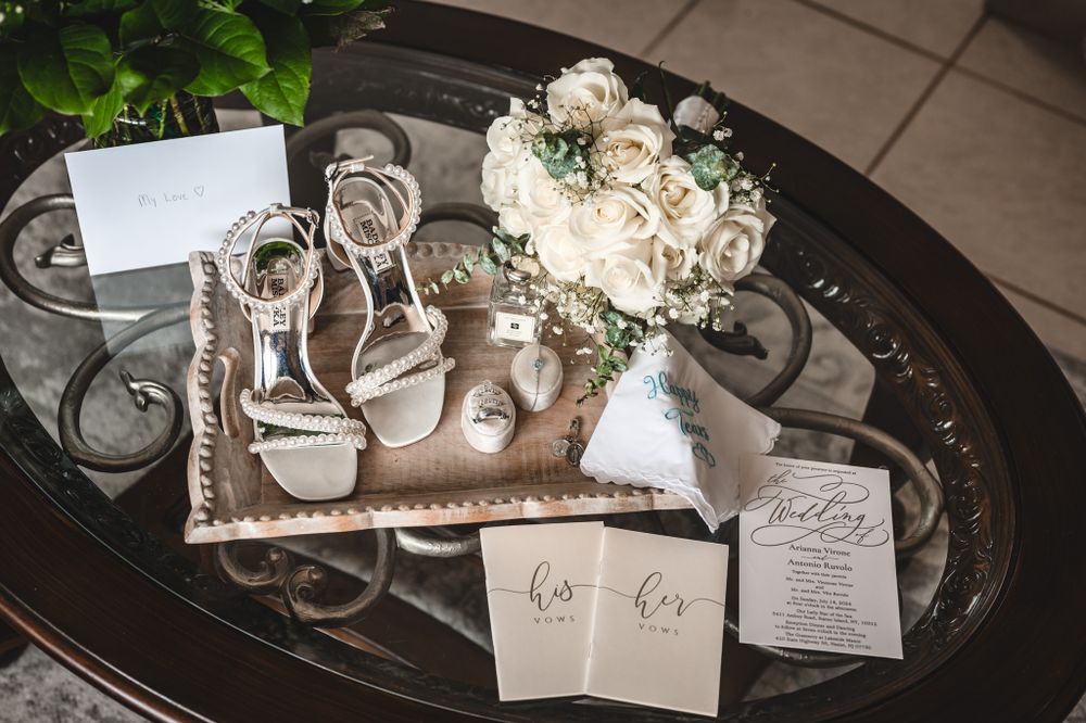Wedding details including invitations, rings, and floral arrangements on dark surface.