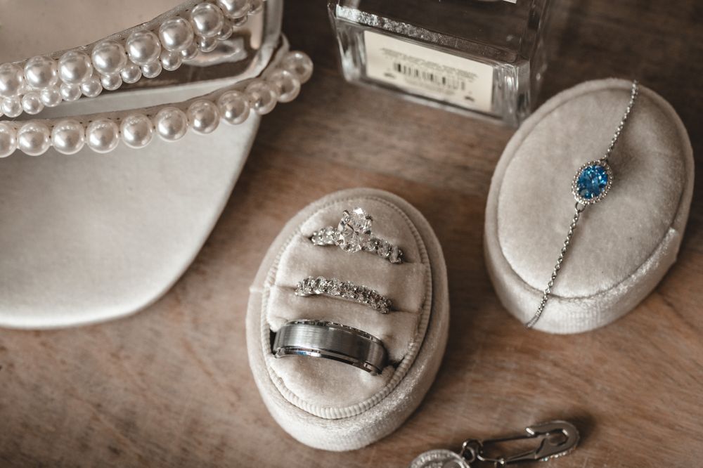 Wedding rings and jewelry displayed on white ring boxes with pearl details.