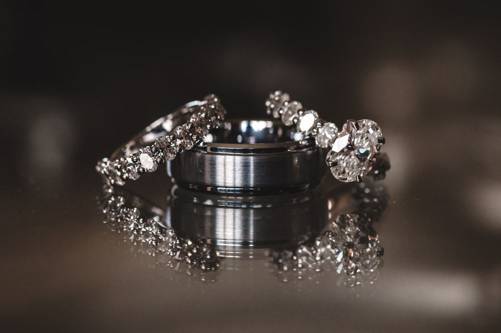 Wedding rings displayed with delicate baby's breath floral arrangements on dark surface.