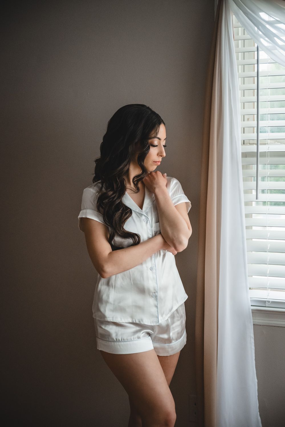 Intimate boudoir photography session featuring soft lighting and white clothing in a bedroom setting.