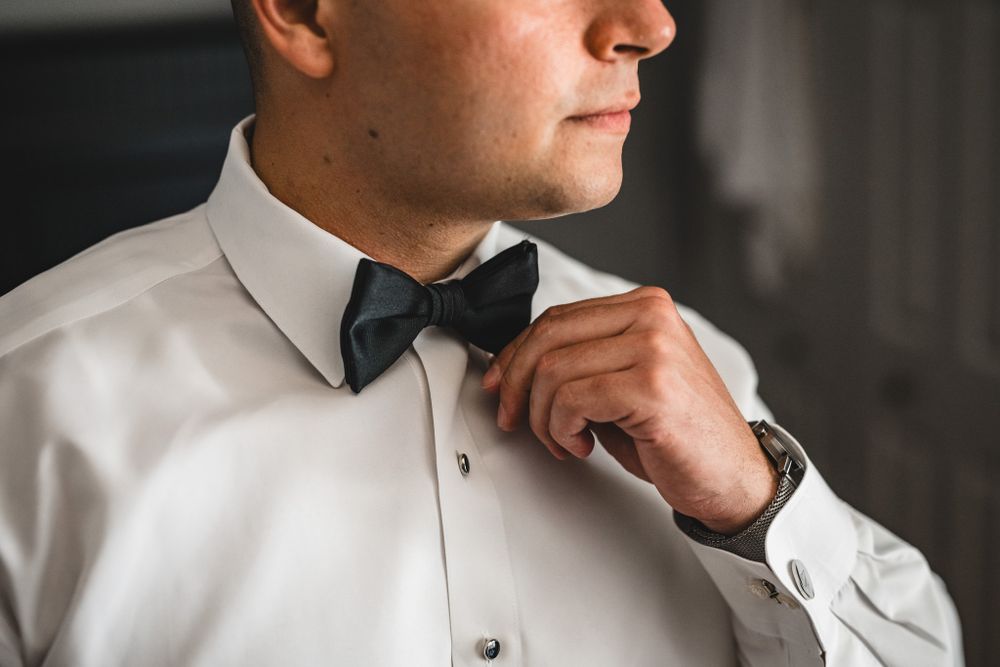 Close up detail shot of a white dress shirt collar and black bow tie.